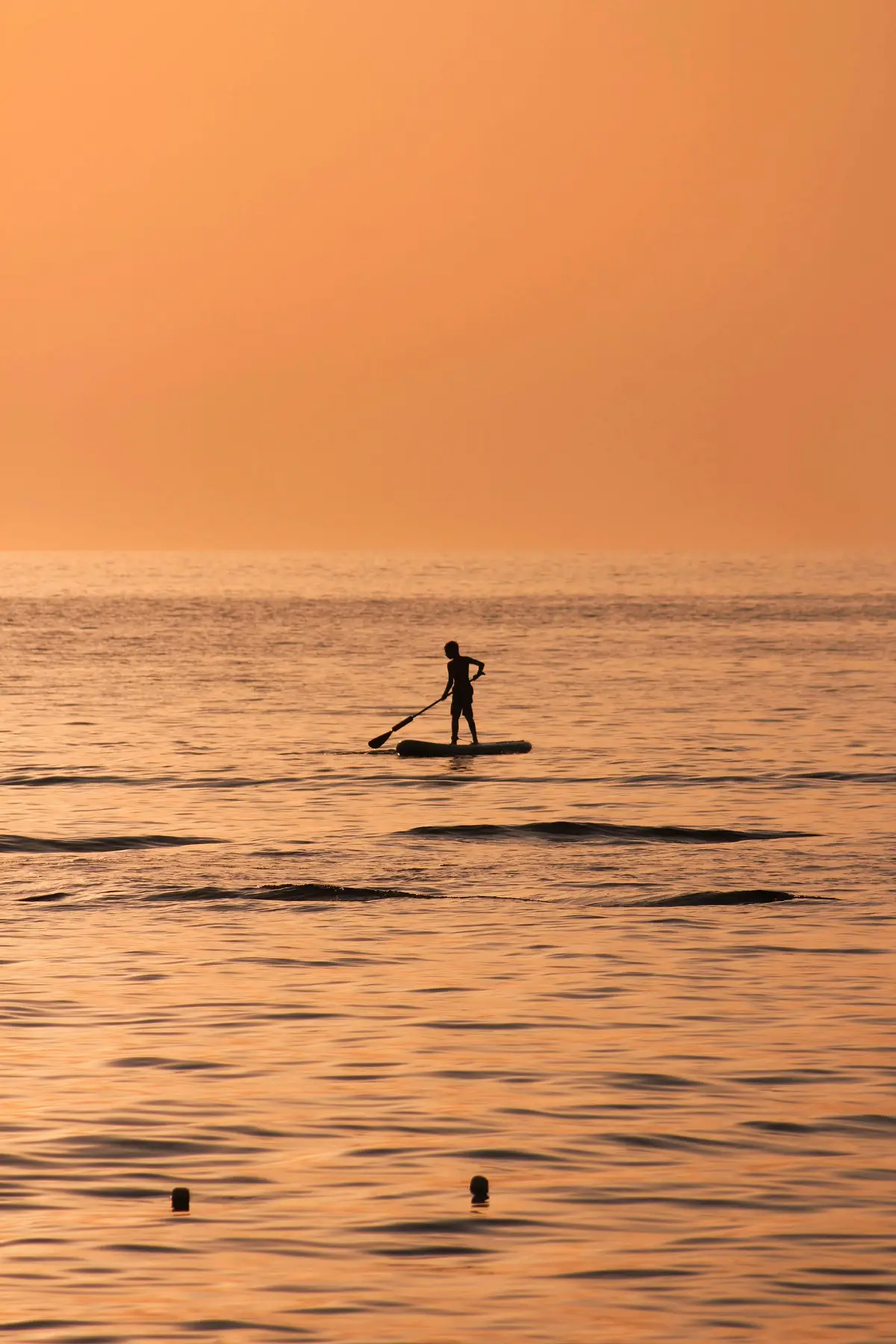 child on a stand-up paddleboard at sunset